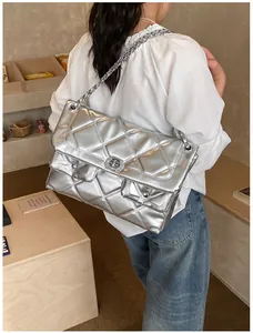 Detail of silver quilted chain bag featuring metallic finish and rectangular turn-lock