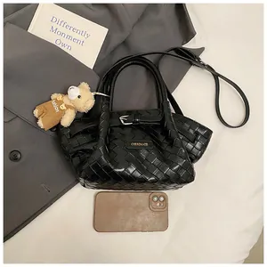 Détail du sac seau noir tressé avec logo, boucle et charmant ours en peluche