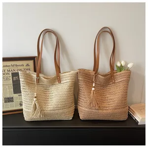 Dettaglio delle borse tote in paglia intrecciata con spalline in pelle e nappe di legno