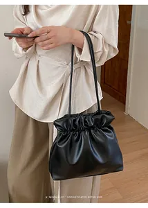 Close-up of a minimalist black pleated leather shoulder bag with sleek slim straps