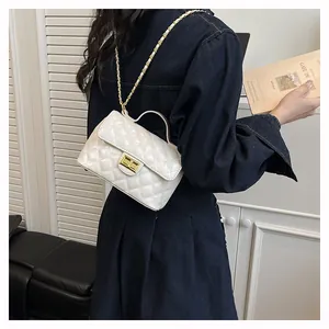 Détail du sac matelassé blanc avec fermoir doré et bandoulière sur robe en jean bleu