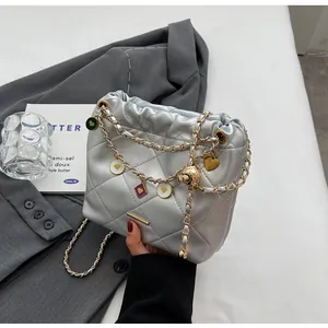 Détails du sac seau matelassé argenté avec chaîne dorée et breloques de cœurs