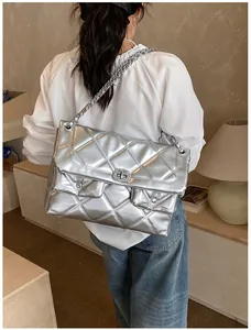 Silver quilted chain bag with large metallic finish worn as a crossbody by model