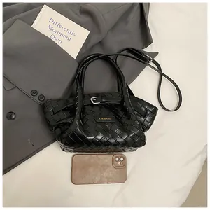 Détail du sac seau noir tressé avec boucle argentée sur une veste de costume grise