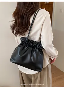Close-up of a black pleated leather bucket bag with minimalist drawstring and retro vibe