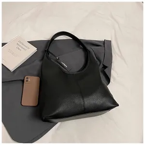 Détails du sac cabas noir en cuir grainé avec coutures précises et pendentif logo