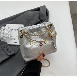 Détail du sac seau matelassé argenté avec chaîne dorée et breloques en forme de cœur