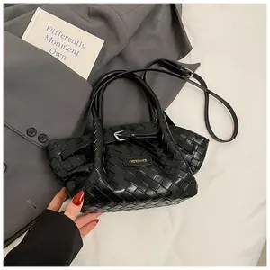 Détail du sac seau noir en cuir tressé avec logo de marque et bandoulière réglable