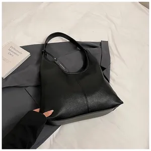 Vue détaillée du cuir noir grainé et de l'étiquette métallique du sac cabas