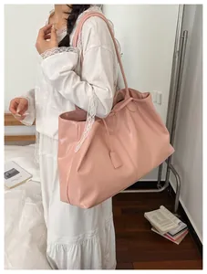 Pink oversized tote bag in glossy faux leather styled with a white lace dress for work