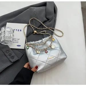 Vue détaillée du sac seau matelassé argenté avec pendentif cœur et chaîne dorée