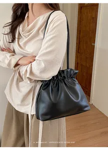 Detail of minimalist black drawstring bucket bag with a sophisticated retro vibe
