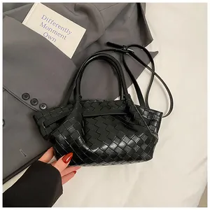 Détail de la texture d'un sac seau noir tressé posé sur un blazer élégant