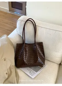 Détail d'un sac cabas tressé marron foncé sur un canapé crème avec une touche rétro chic