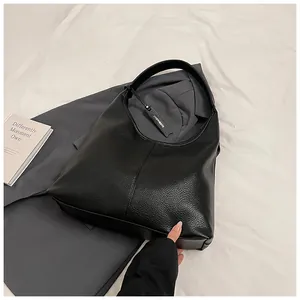 Détail de la texture litchi noire sur un grand sac hobo avec une étiquette de marque