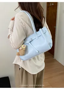 Light blue leather tote bag side view with brown teddy bear charm and silver buckle