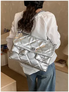 Detailed view of silver quilted crossbody bag with metallic chain and large capacity on model