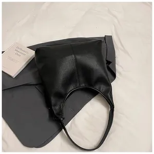 Gros plan sur la texture en cuir noir et les coutures verticales de ce sac hobo chic