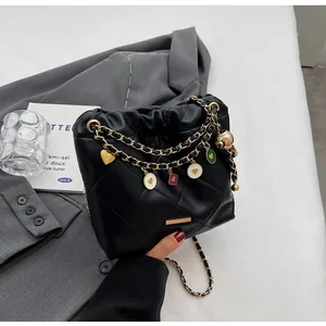 Détail du sac seau noir matelassé avec chaînes dorées et breloques en émail coloré