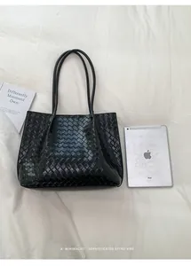 Détail d'un sac cabas noir tissé avec texture Intrecciato et finition cuir élégante