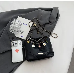 Vue détaillée du sac seau noir matelassé avec breloques dorées et bandoulière