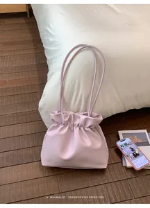 Close-up of a lilac pleated cloud bucket bag with thin straps on a white bedding background