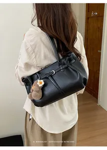 Detailed side view of black matte PU leather tote bag with a plush bear charm and buckle