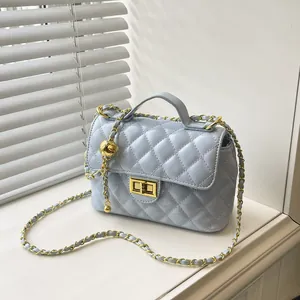 Sac matelassé bleu clair avec chaîne dorée et breloque sphérique sur rebord de fenêtre