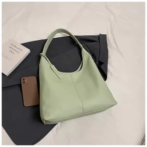 Détail du cuir grainé vert clair d'un grand sac cabas avec étiquette de marque élégante
