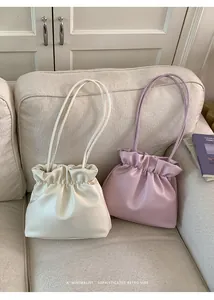 Detail of minimalist bucket bags in beige and lavender with pleated soft leather texture