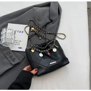 Vue détaillée du sac seau noir matelassé avec chaîne dorée et breloques en émail