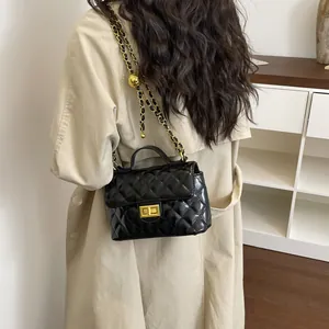 Sac bandoulière matelassé noir avec chaîne dorée sur modèle en manteau beige