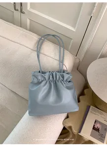Detail of light blue pleated cloud bucket bag on beige fabric sofa in home setting