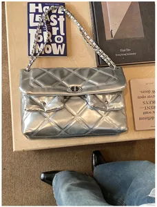 Close-up of silver quilted texture on flap bag with dual front pockets and chain strap