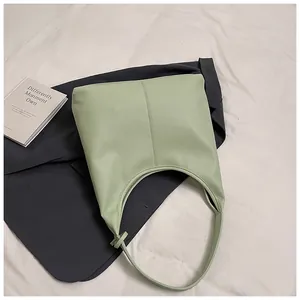Gros plan d'un sac cabas en cuir grainé vert menthe sur une veste grise