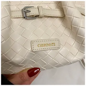 Détail du sac seau en cuir tressé crème avec bandoulière réglable et boucle en métal