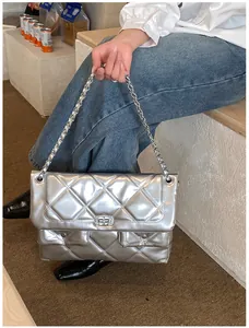 Detail of silver metallic quilted handbag featuring rhinestone lock and chain strap
