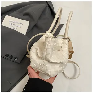 Détail du sac seau tissé blanc cassé avec texture cuir et charm d'ours