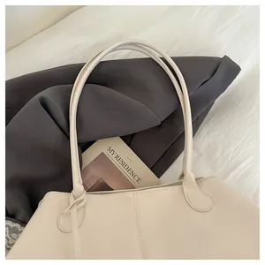 Detail of off-white leather tote bag with vertical stitching on a grey blazer