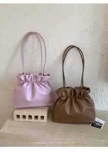 Detailed view of minimalist pleated bucket bags in lavender and coffee brown matte leather