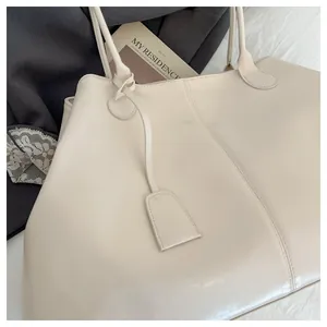 Close-up of cream large tote bag with glossy leather texture and stylish bag charm