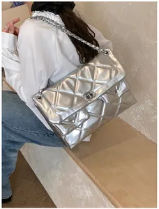 Close-up of quilted silver crossbody tote with chain strap and rhinestone lock details