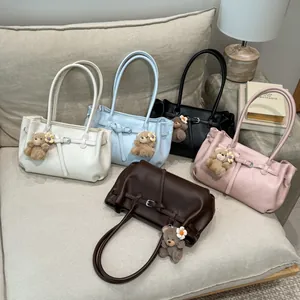 Minimalist soft leather tote bag with teddy bear pendant in five colors on a sofa