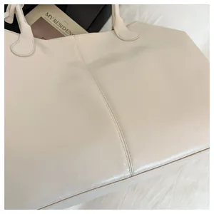 Macro detail of creamy white tote bag showing soft textured leather and stitching