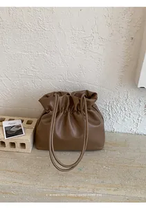 Detail of dark brown gathered pouch bag showing soft faux leather and minimalist design