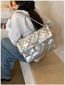Detailed view of silver quilted chain bag worn by model in a cozy cafe setting