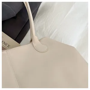 Detailed close-up of neat stitching and durable strap connection on off-white tote bag