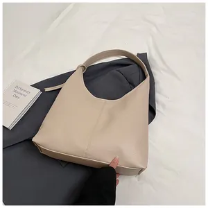 Détail de la texture cuir beige à motif litchi sur un grand sac hobo à bandoulière