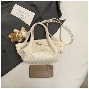 Vue détaillée du sac seau tressé blanc cassé avec pendentif ours et bandoulière