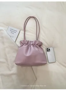 Detailed top view of light purple pleated shoulder bag on minimalist linen surface